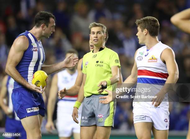 Todd Goldstein of the Kangaroos speaks with the umpires following a contentious ball up decision as Josh Dunkley of the Bulldogs looks on during the...