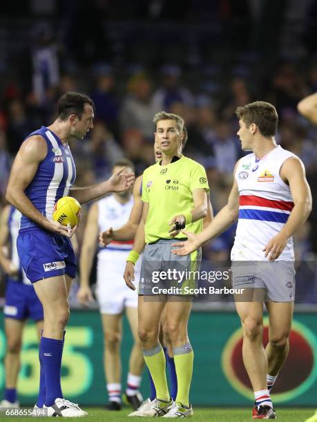 Todd Goldstein of the Kangaroos speaks with the umpires following a contentious ball up decision as Josh Dunkley of the Bulldogs looks on during the...