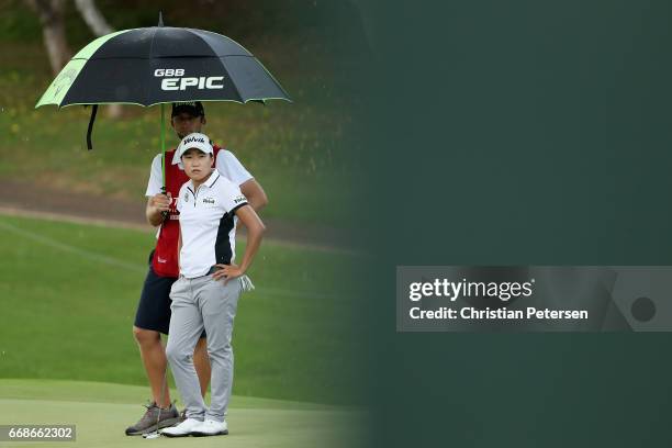 Ilhee Lee of Republic of Korea stands under an umbrella with her caddie on the fourth green during the third round of the LPGA LOTTE Championship...