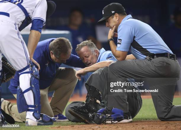 Home plate umpire Dale Scott is tended to by a Toronto Blue Jays trainer as first base umpire Jim Reynolds looks on after Scott took a foul ball in...