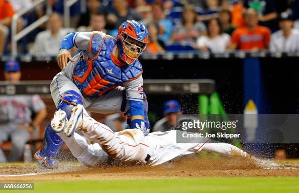 Miguel Rojas of the Miami Marlins is tagged out at home in the eighth inning by Rene Rivera of the New York Mets at Marlins Park on April 14, 2017 in...