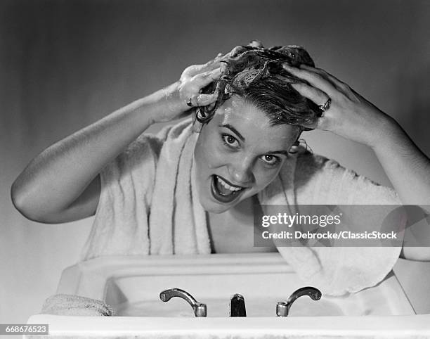 1950s SMILING WOMAN WASHING SHAMPOOING HAIR IN SINK LOOKING AT CAMERA