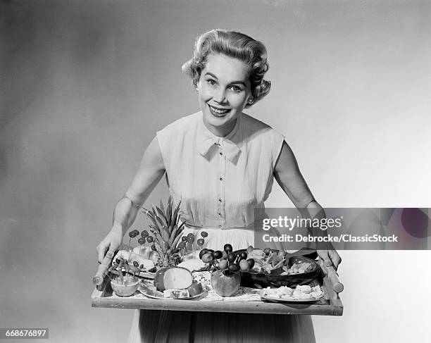 1950s SMILING WOMAN HOSTESS HOLDING TRAY OF FRUIT CHEESE CANAP?S HORS DOEUVRES PARTY FOOD