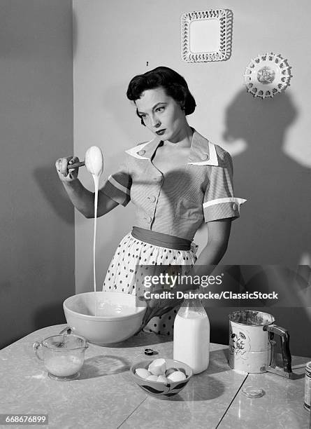 1950s DISTRACTED HOUSEWIFE MIXING BREAKFAST PANCAKE BATTER IN KITCHEN