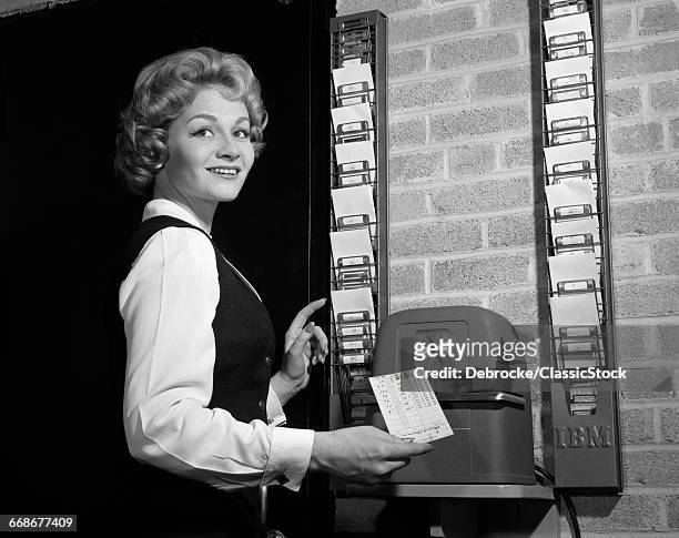 1960s 1950s WOMAN IN OFFICE WITH TIMECARD AND TIMECARD CLOCK