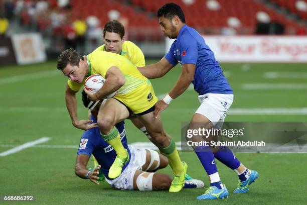 Ed Jenkins of Australia is tackled by Savelio Ropati of Samoa during the 2017 Singapore Sevens match between Australia and Samoa at National Stadium...