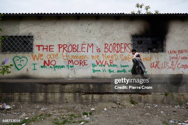 Woman walks past an abandoned wearhouse on April 14, 2017 in Belgrade, Serbia. Migrants and refugees are taking shelter in derelict buildings...