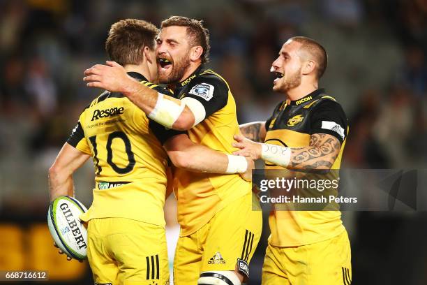 Beauden Barrett of the Hurricanes celebrates with Callum Gibbins and TJ Perenara after scoring a try during the round eight Super Rugby match between...
