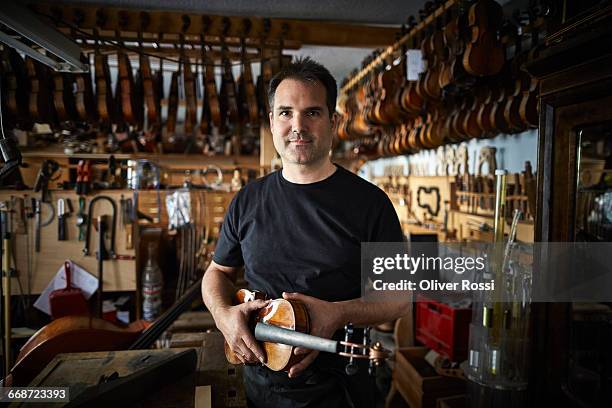 portrait of luthier in workshop holding violin - instrument maker fotografías e imágenes de stock