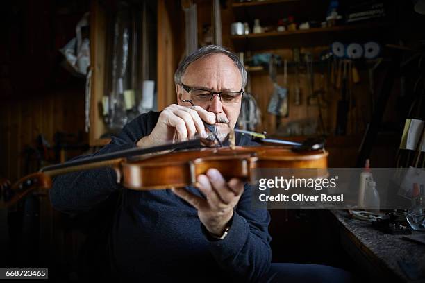 luthier in workshop working on violin - instrumentenmaker stockfoto's en -beelden