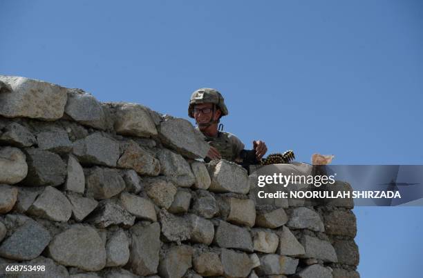 Soldier stands guard near the site of a US bombing during an operation against Islamic State militants in the Achin district of Nangarhar province on...