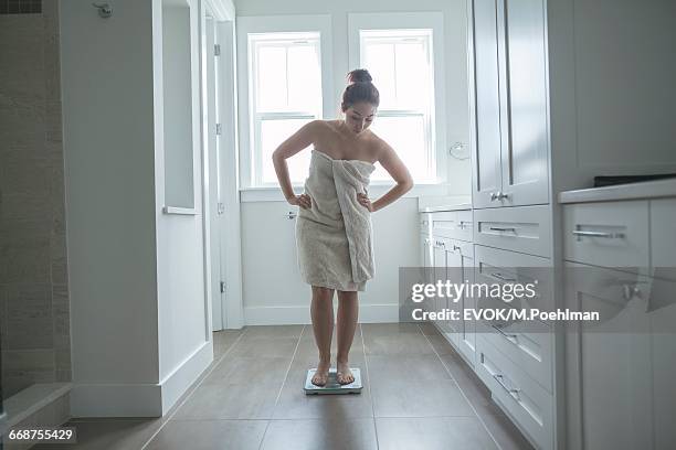 young woman on bathroom scale - hand in die hüfte gestemmt stock-fotos und bilder