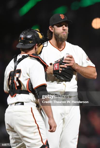 Tim Federowicz of the San Francisco Giants walks to the mound to talk with pitcher Madison Bumgarner against the Colorado Rockies in the top of the...