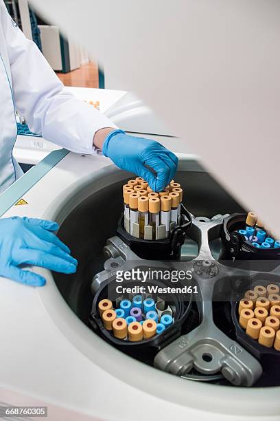 laboratory technician in analytical laboratory taking test tubes out of centrifuge - centrifugal force fotografías e imágenes de stock