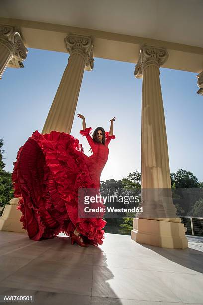 woman dressed in red dancing flamenco on terrace at backlight - flamencos stock-fotos und bilder