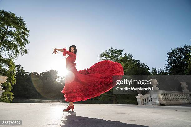 woman dressed in red dancing flamenco on terrace at backlight - flamencos fotografías e imágenes de stock