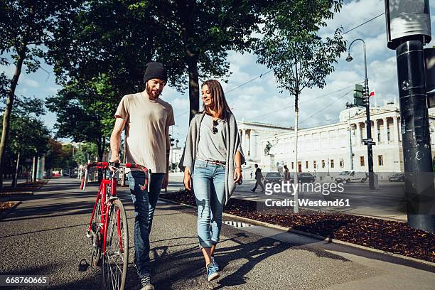 austria, vienna, young couple with bicycle in front of parliament building - walking with bike stock-fotos und bilder