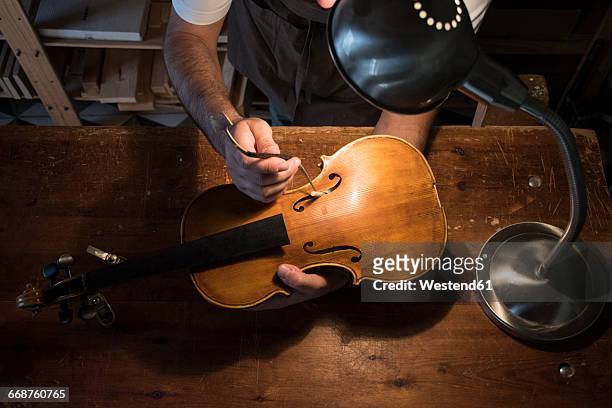 luthier adjusting the sound post of a violin in his workshop - instrument maker stock pictures, royalty-free photos & images