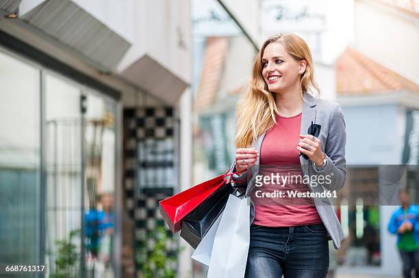 smiling woman walking on the street carrying shopping bags - window shopping stock-fotos und bilder
