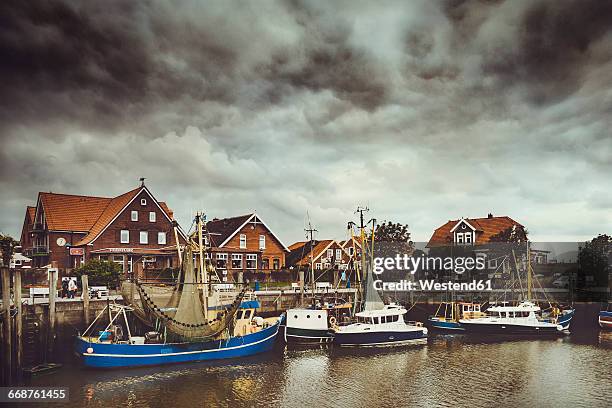 germany, lower saxony, greetsiel, neuharlingersiel, fishing harbour and angry clouds - ostfriesland stock-fotos und bilder