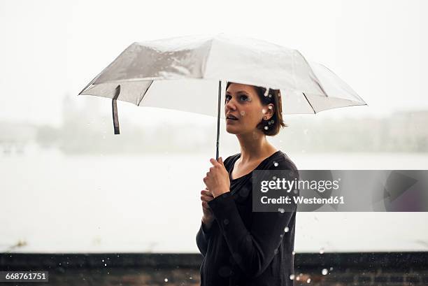 woman with umbrella on a rainy day - torrential rain umbrella stock pictures, royalty-free photos & images