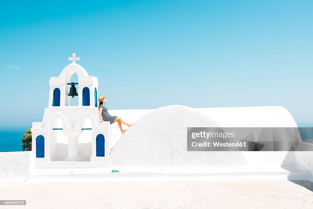 Greece, Santorini, Oia, woman sitting on spur of belltower