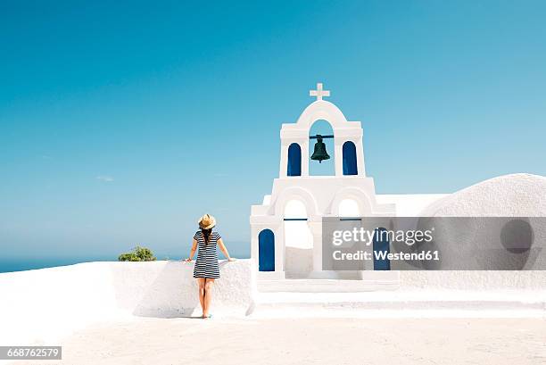 greece, santorini, oia, back view of woman standing next to bell tower looking to the sea - greek islands ストックフォトと画像