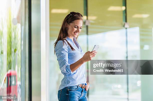 smiling brunette woman looking at cell phone - brunette smiling stock-fotos und bilder