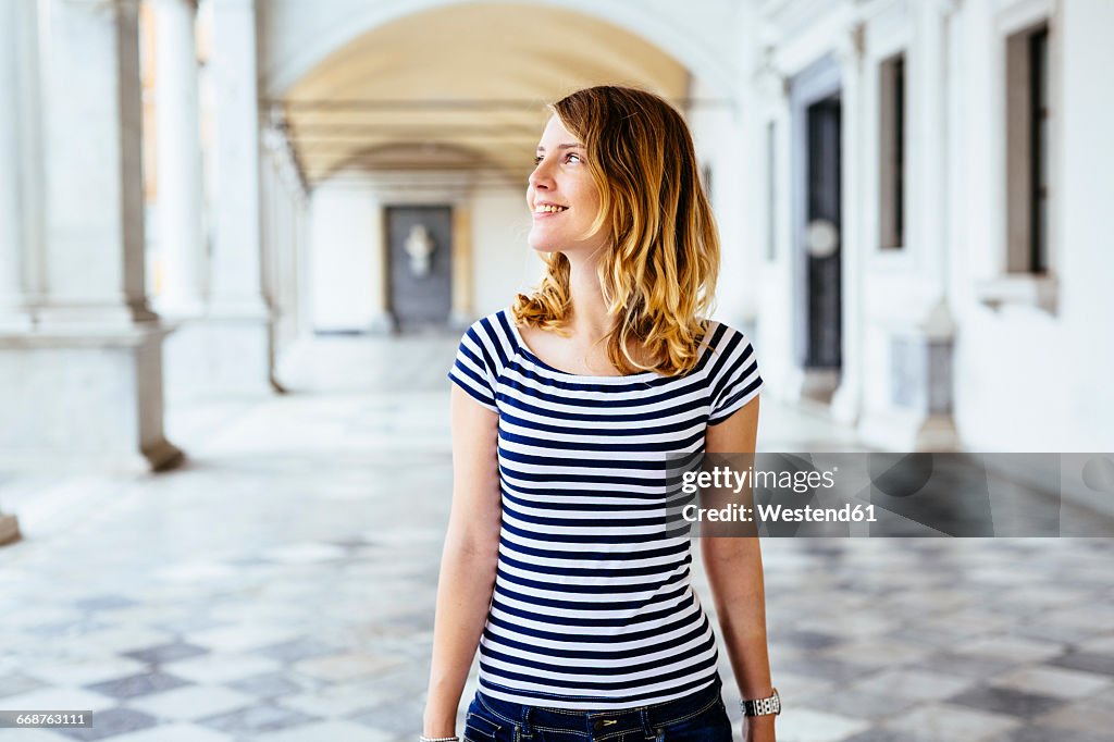 Italy, smiling young woman watching something