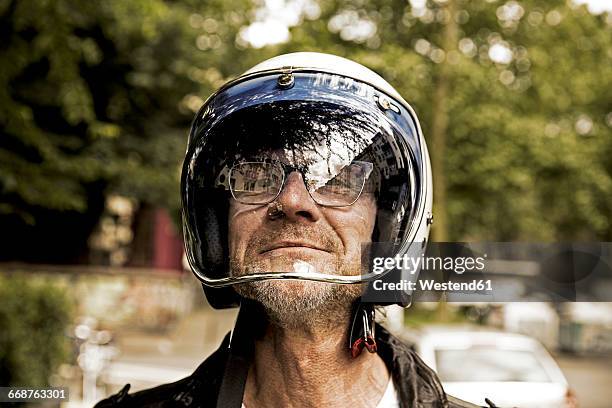 portrait of smiling biker looking through vizor of his motorcycle helmet - motociclista fotografías e imágenes de stock