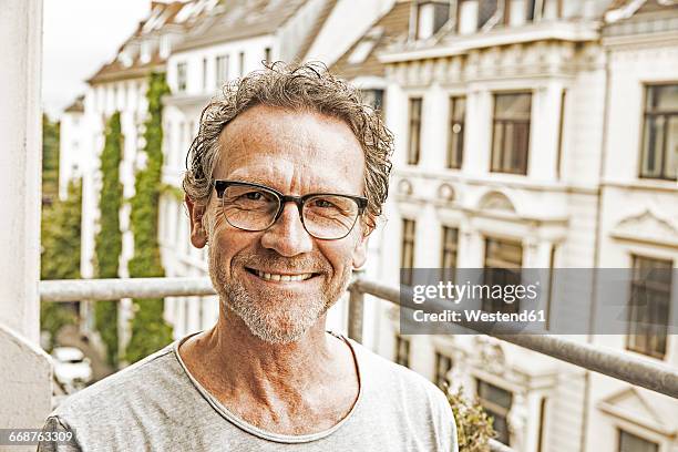 portrait of happy man wearing glasses on his balcony - デサチュレート ストックフォトと画像