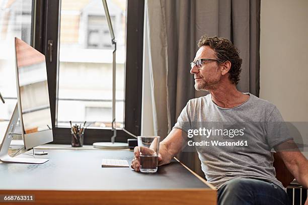 man sitting at desk looking at computer - water glasses ストックフォトと画像