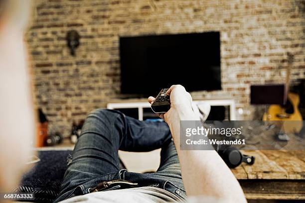 man lying on the couch using remote control, partial view - feet up tv stock pictures, royalty-free photos & images