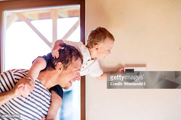 father carrying son on shoulders, adjusting thermostat - termostato - fotografias e filmes do acervo