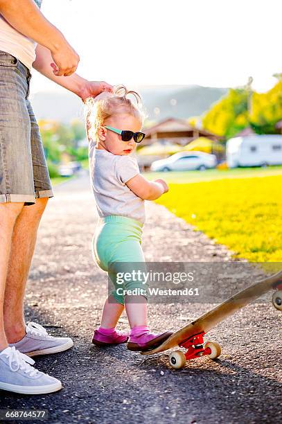 portrait of toddler girl wearing sunglasses kicking skateboard - baby kicking stock pictures, royalty-free photos & images