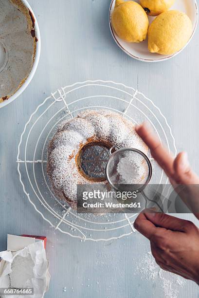 woman's hands sprinkling icing sugar on ring cake - kugelhopf foto e immagini stock
