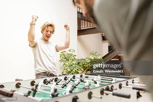 colleagues playing table football in office - totó - fotografias e filmes do acervo