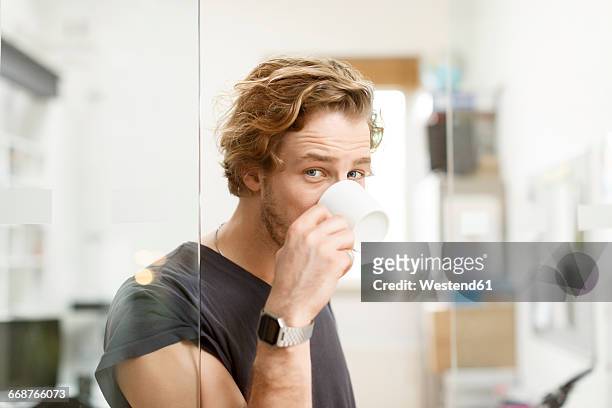 young man drinking coffee in office - solo un uomo giovane foto e immagini stock