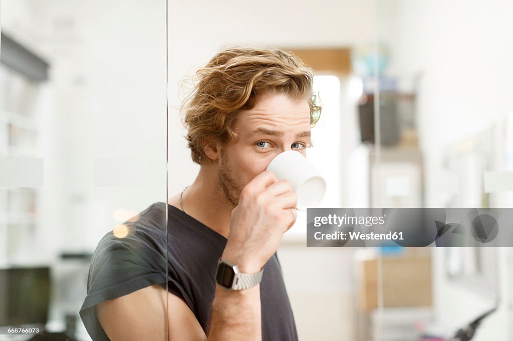 Young man drinking coffee in office