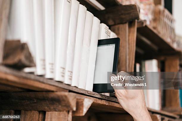 hand taking e-book from book shelf - lector de libros electrónicos fotografías e imágenes de stock