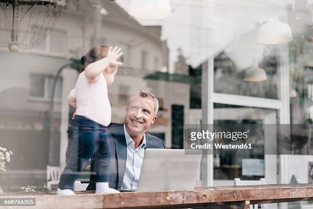 businessman with little daughter working on laptop in cafe - flexible work stock-fotos und bilder