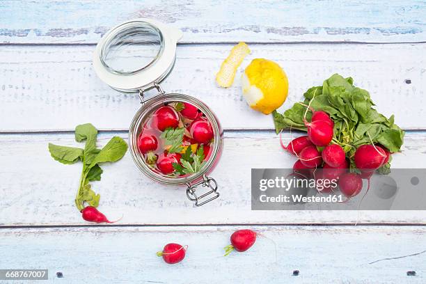 glass of pickled red radishes and ingredients on wood - eingelegtes stock-fotos und bilder