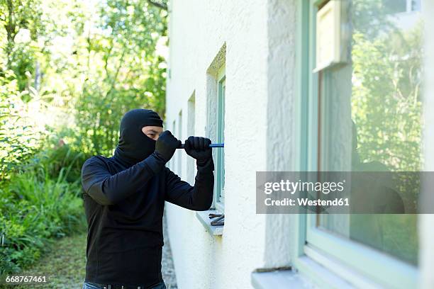 burglar with crowbar breaking window - haus einbruch stock-fotos und bilder