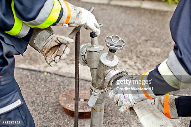 close-up of firefighters connecting hose to fire hydrant - feuerwehr deutschland stock-fotos und bilder