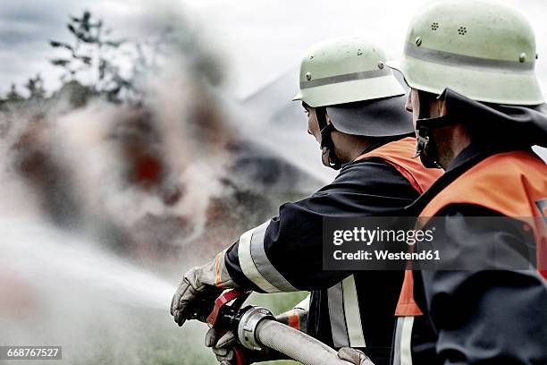 fire brigade extinguishing fire - feuerwehrschlauch stock-fotos und bilder