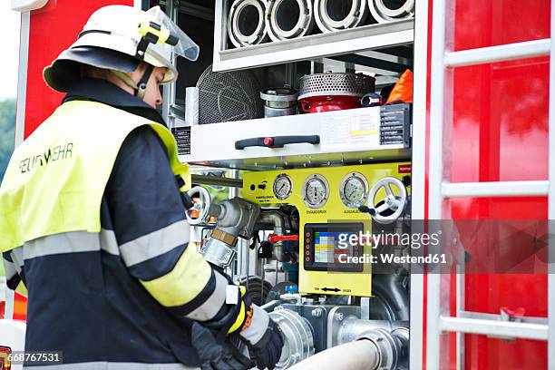 firefighter at fire engine - feuerwehr deutschland stock-fotos und bilder