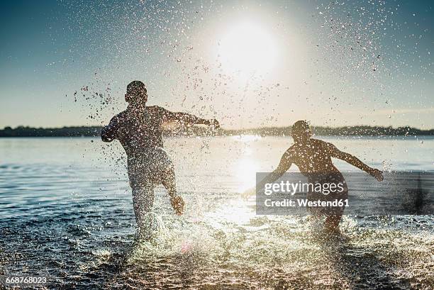 couple squirting each other with water - menschen wasser stock-fotos und bilder