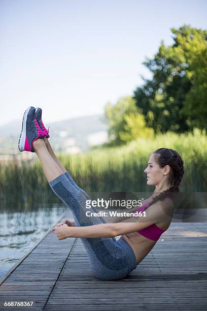 young woman doing exercise at lake - abs fotos imagens e fotografias de stock