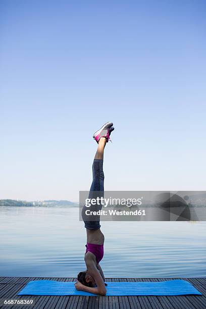 young woman doing exercise on pier, headstand - shirshasana stock pictures, royalty-free photos & images