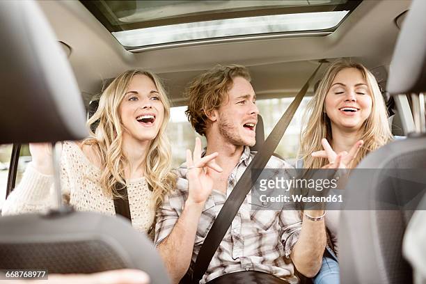 three friends sitting on backseat of car singing together - friends inside car 個照片及圖片檔